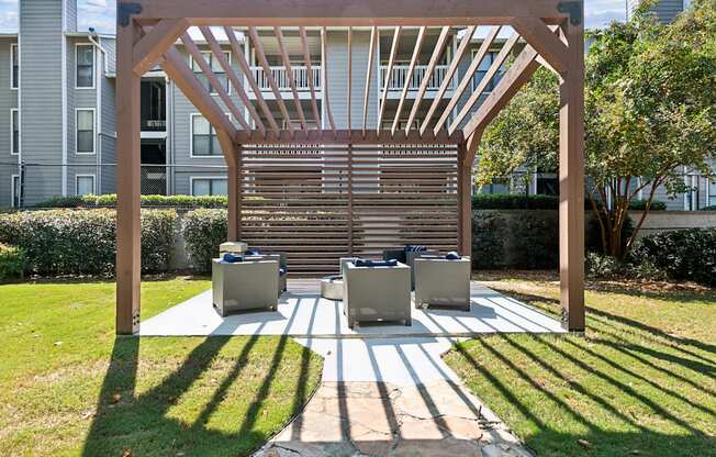a covered patio with chairs and a wooden pergola