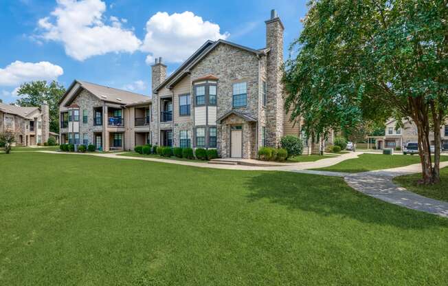 a large house with a green lawn and trees in front of it