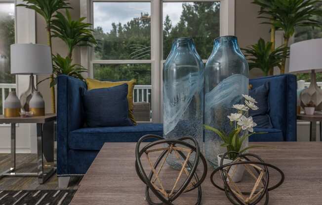 a living room with blue couches and a table with vases