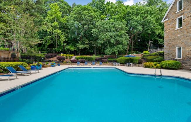 A large swimming pool surrounded by trees and a stone building. at Mill House at East Cobb, Marietta Georgia