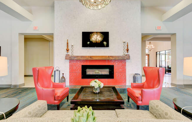 a living room with red chairs and a fireplace