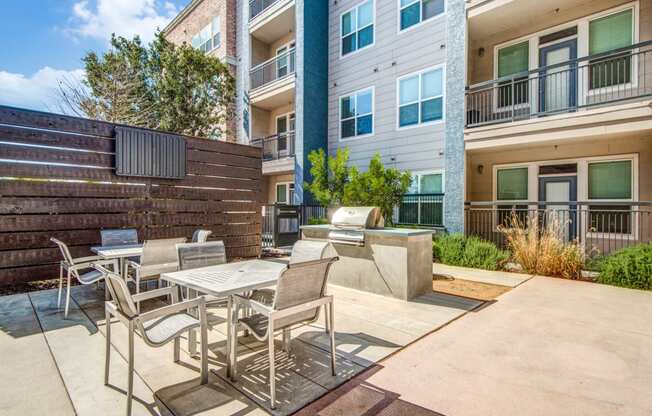 a patio with a table and chairs and a fire pit in front of an apartment building