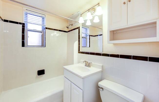 bath room with view of toilet, vanity, tub, and window at cambridge square apartments in bethesda md