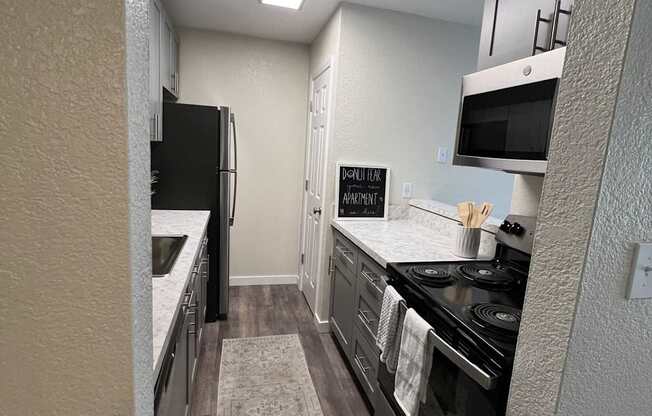 A kitchen with a black refrigerator, stove, and a rug on the floor.