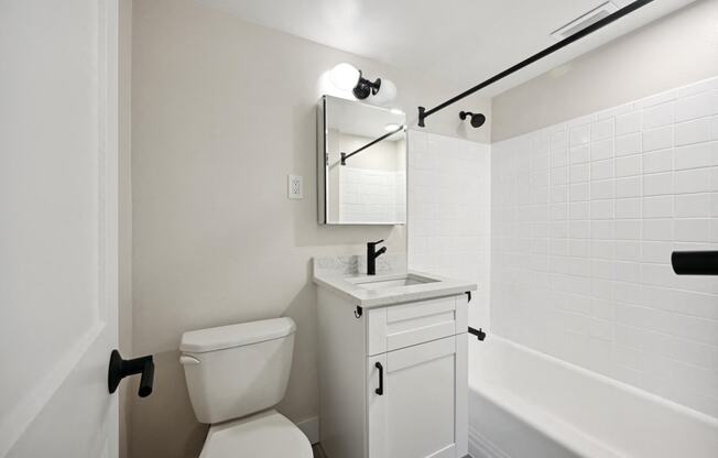 a white bathroom with a toilet and a sink and a tub