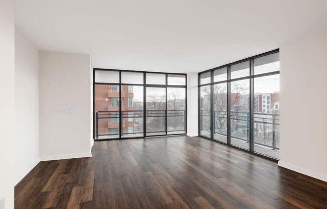 A room with wooden floors and large windows overlooking a cityscape.