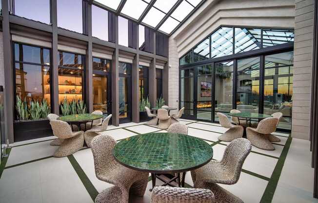 A glass-roofed room with a green table and chairs.