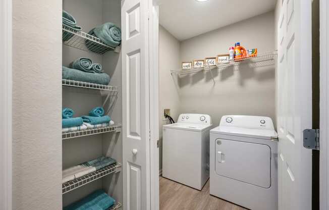 a laundry room with a washer and dryer and a closet with shelves