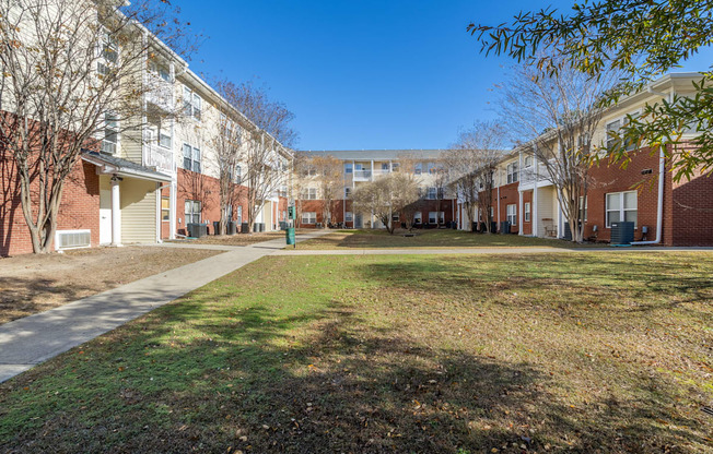 a grassy area in front of a row of brick apartment buildings