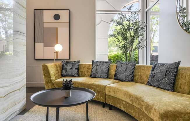 A living room with a yellow couch and a round table.