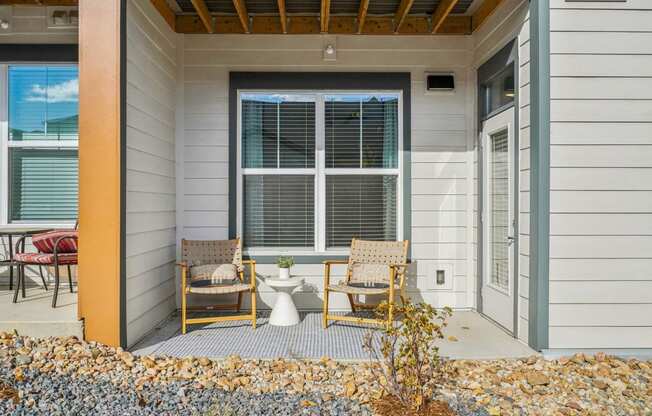 a front porch with two chairs and a toilet on it