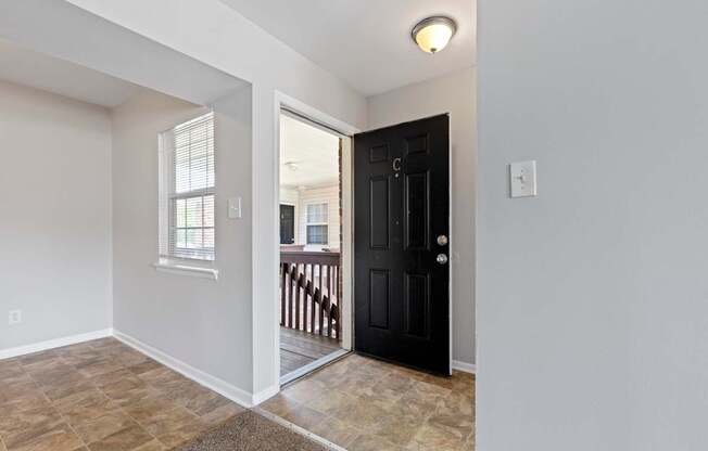 the entrance to a home with a black door and tile flooring