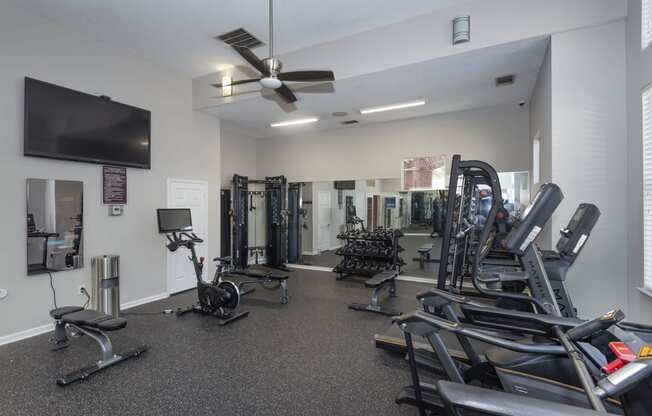 a spacious fitness center with cardio equipment and a flat screen tv at Seasons at Umstead apartments in Raleigh