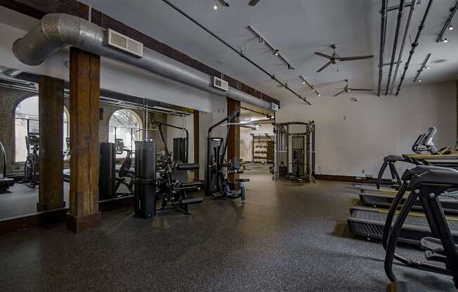 A gym with a variety of equipment including treadmills, weights, and exercise machines.