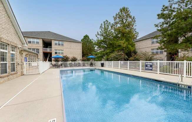 A swimming pool in front of a building with a blue sky in the background.
