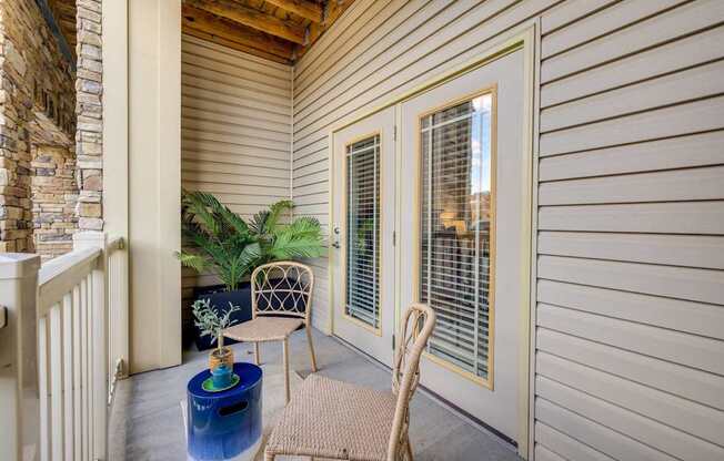 A patio with a chair, table, and potted plant.