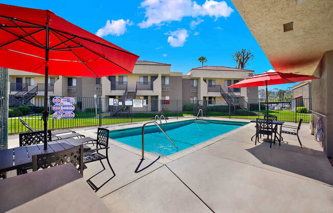 A pool area with red umbrellas and a blue pool.