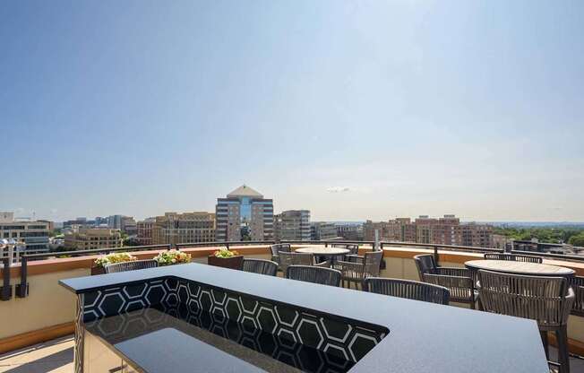 a rooftop patio with tables and chairs and a view of the city