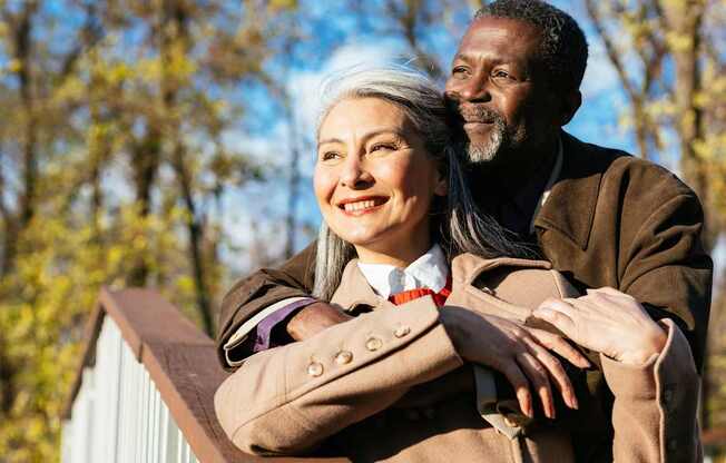 A man and a woman are standing close together on a bridge.