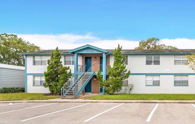 a blue and white building with stairs and a parking lot