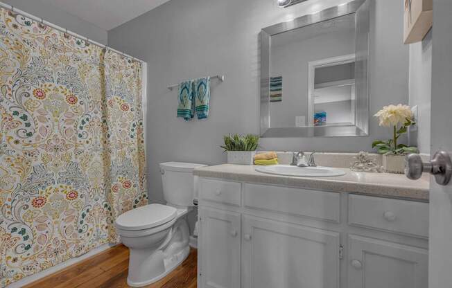 A white bathroom with a floral shower curtain.