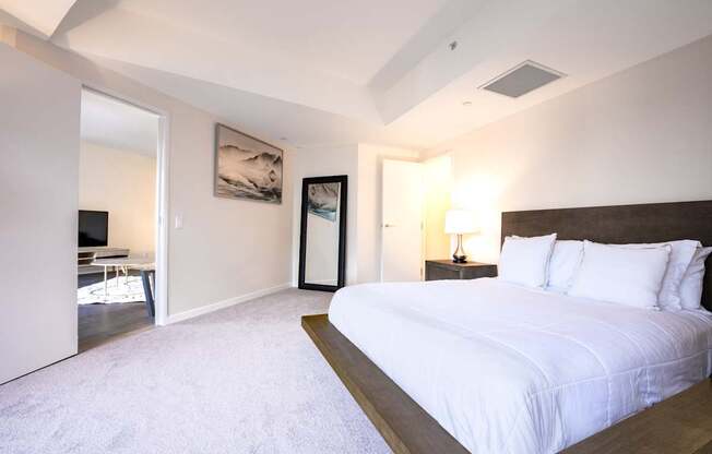 A bedroom with a large bed and a painting on the wall.