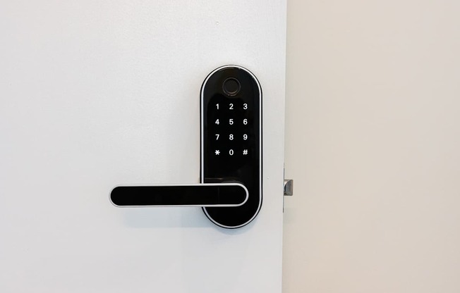 A black keypad is mounted on a white wall at Skylar At Sunset Apartments, Los Angeles, California