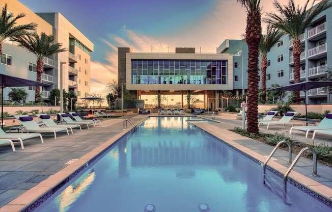 A large swimming pool surrounded by lounge chairs and palm trees.