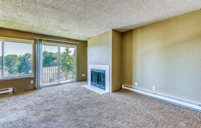 an empty living room with a fireplace and sliding glass doors