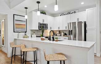 A kitchen with white cabinets and a white island with two barstools. at The Laurel Apartments, Arizona