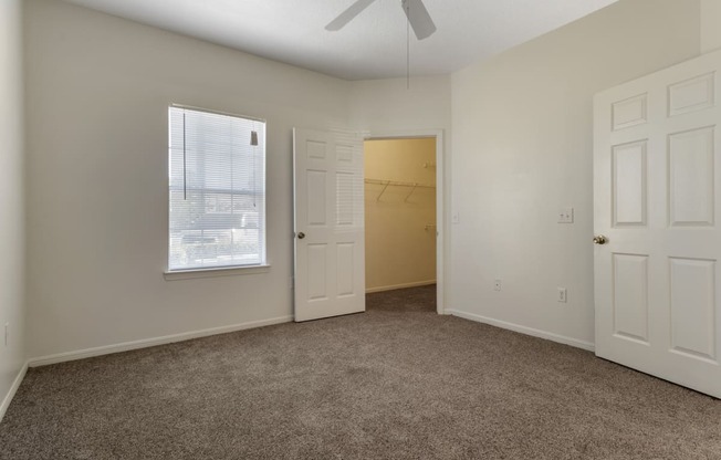 an empty bedroom with a closet and a window