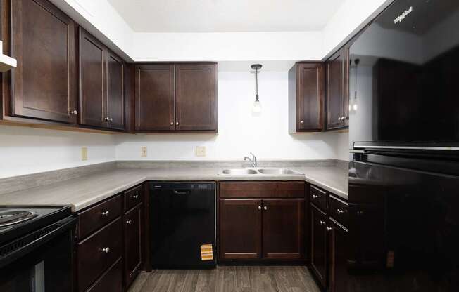 A kitchen with dark wood cabinets and black appliances.