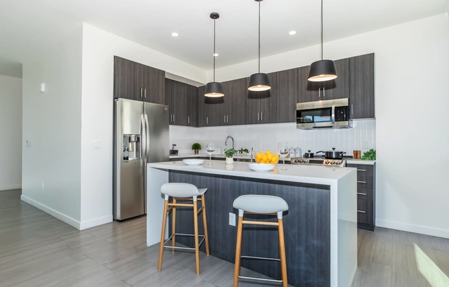 A modern kitchen with a large island and bar stools.
