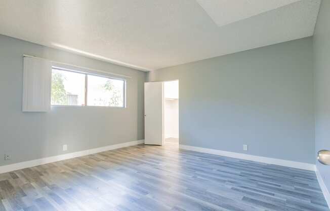 an empty living room with wood floors and a window