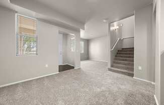 A spacious room with a staircase and a window with blinds.