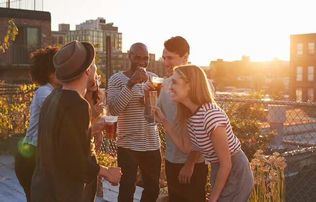 a group of people standing on a rooftop talking and drinking wine