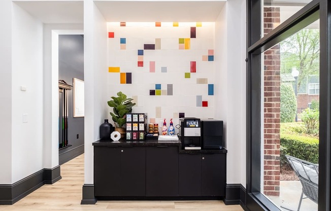 a lobby with a black bar and a coffee machine and a colorful wall with tiles