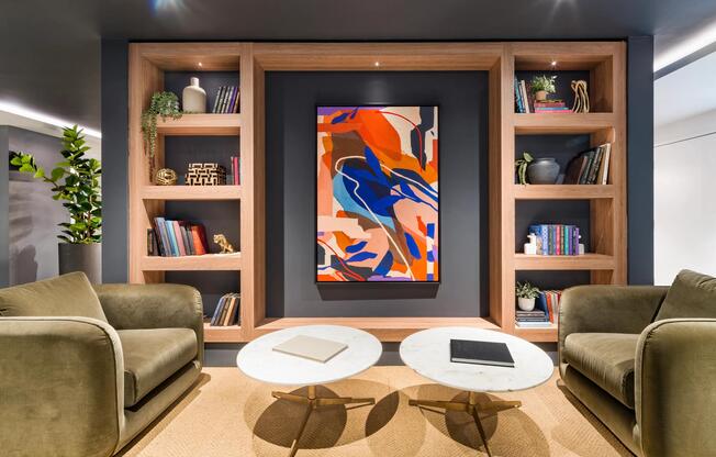 A thoughtfully designed lounge at Modera Aventura, where custom shelving, curated artwork, and layered textures create a polished setting for conversation or quiet focus.