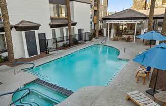 a swimming pool with chairs and umbrellas in front of a building