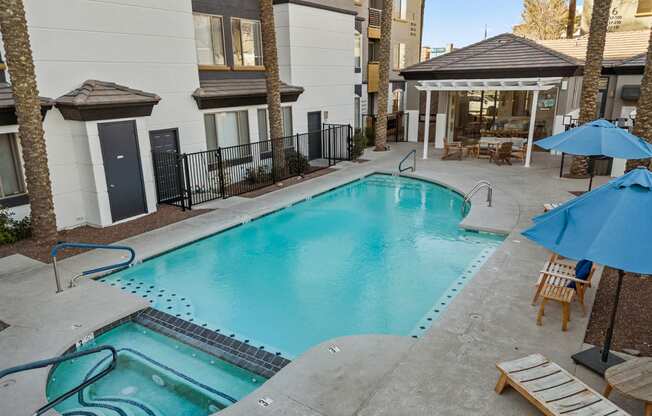 a swimming pool with chairs and umbrellas in front of a building