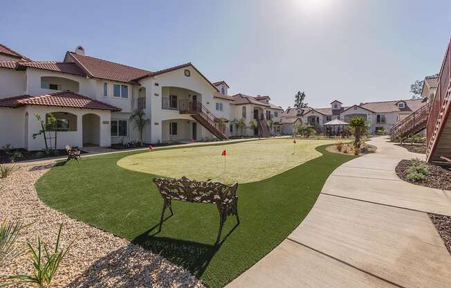 A sunny day at a residential area with houses and a bench.