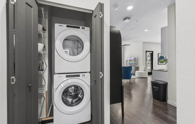 A modern laundry room with a washer and dryer built into a cabinet.