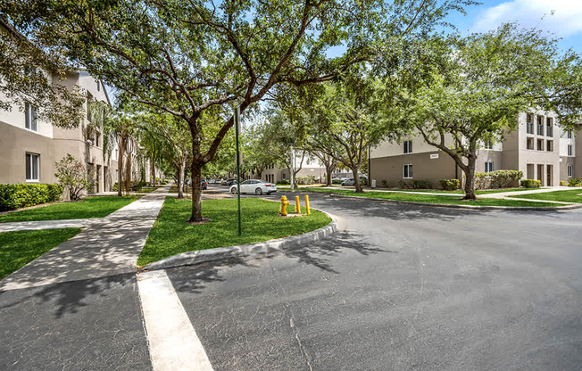 A tree-lined street with apartment buildings on either side.