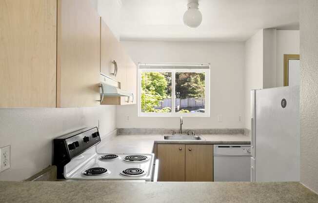 a kitchen with a stove top oven next to a sink at Mill Pond Apartments, Washington