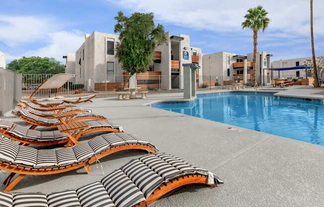 a pool with lounge chairs and palm trees in the background