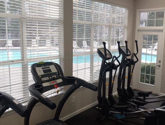 a group of exercise machines in a room with a pool