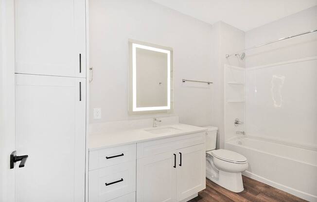 A white bathroom with a toilet, sink, and bathtub.