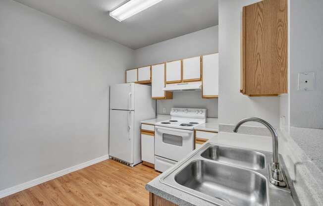 an empty kitchen with white appliances and wood flooring