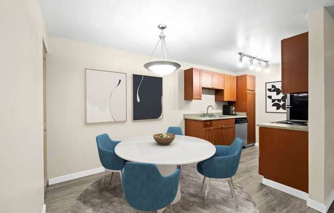 a dining area with a table and chairs and a kitchen in the background