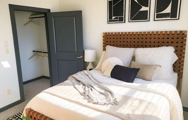 A bedroom with a bed, a wardrobe, and a wall-mounted shelf.
